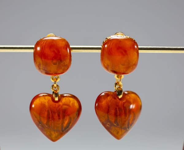 Yves SAINT LAURENT - Paire de boucles d'oreilles en coeur, imitation ambre et métal doré, signées.