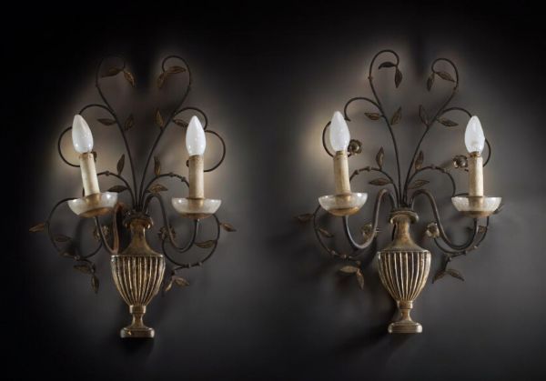 A pair of patinated metal sconces decorated with antique-style vases.