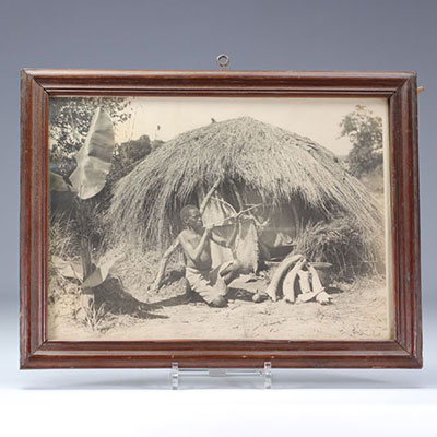 An old African photograph showing an individual in his hut