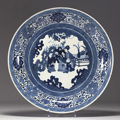 China - Large blue-white porcelain dish decorated with flowers and figures, Kangxi mark in a double circle.