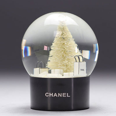 Boule à neige CHANEL représentant le flacon du parfum CHANEL n° 5 avec des sacs cadeaux CHANEL, d'un sapin et surmonté du logo CC