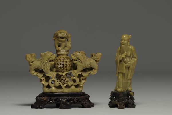 Chine - Ensemble de deux sculptures en pierre dure, une à décor de lions et un Sage, sur socles en bois.