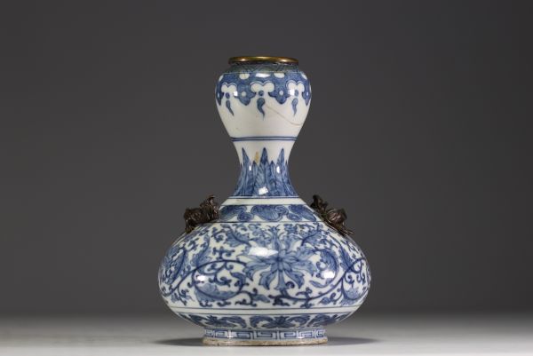 China - A white-blue porcelain vase with floral decoration surmounted by two bronze chimeras.