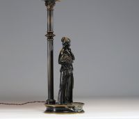 Lampe en bronze représentant une femme à l'antique adossée sur une colonne, socle en marbre noir.