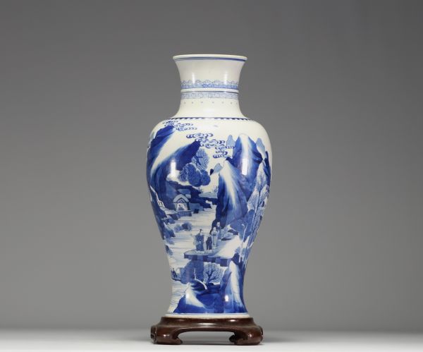 China - White and blue porcelain vase decorated with landscape and characters, wooden base, blue mark under the piece.