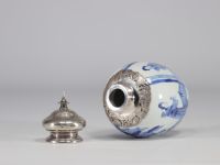 A white and blue vase decorated with women surmounted by a silver stopper with a mark under the piece from the Kangxi period (1661-1722)