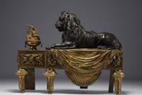 Paire de chenets en bronze patiné et doré représentant des lions couchés devant une flamme, XIXème.