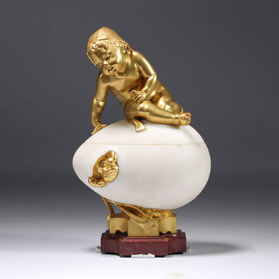 Covered marble and bronze box forming an egg with a child on top