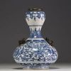 China - A white-blue porcelain vase with floral decoration surmounted by two bronze chimeras.