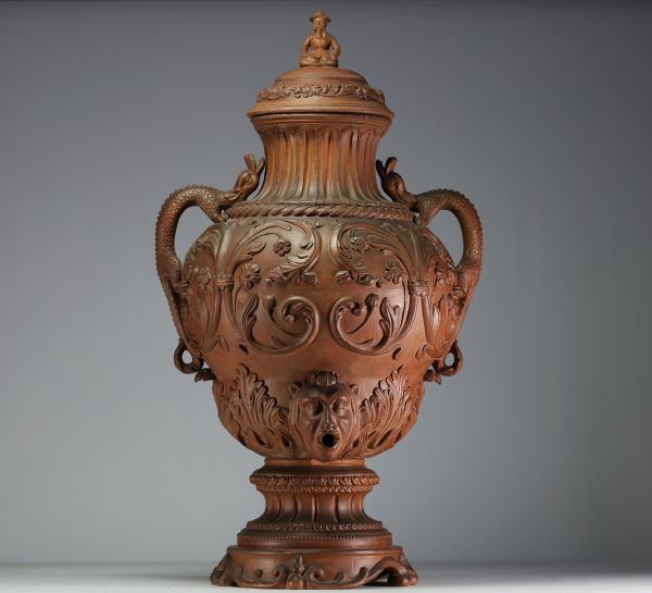 Imposing terracotta wine fountain decorated with scrolls of flowers, chimera-shaped handles, lid surmounted by a Chinese figure.