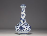 China - A white-blue porcelain vase decorated with a chimera in relief winding around the neck and floral motifs, 18th century.