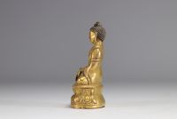 Sculpture of a seated Buddha on a gilded bronze base