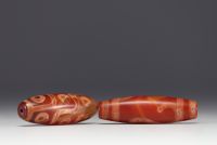 Tibet - Pair of Dzi amulets, one with ‘9 eyes’ in red agate, fine specimens from the 19th century.