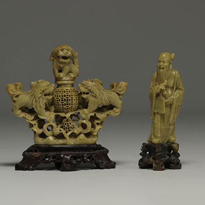 Chine - Ensemble de deux sculptures en pierre dure, une à décor de lions et un Sage, sur socles en bois.