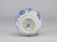 A white and blue vase decorated with women surmounted by a silver stopper with a mark under the piece from the Kangxi period (1661-1722)