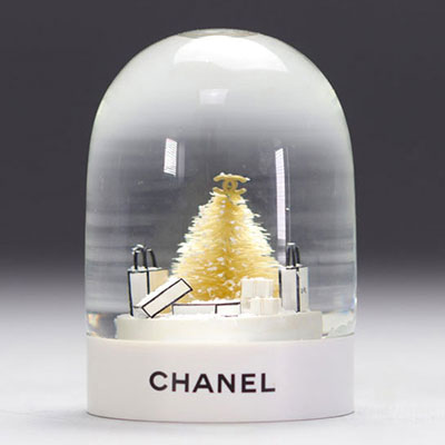 Boule à neige CHANEL ornée de sacs CHANEL, d'un sapin et surmonté du logo CC et socle pvc avec l'inscription