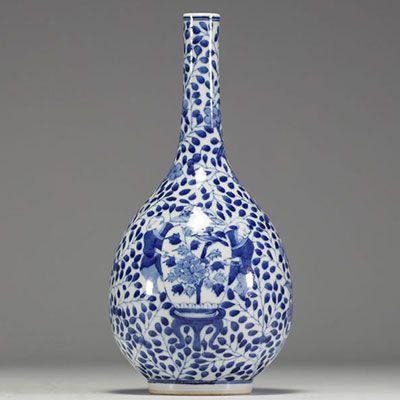 China - White-blue porcelain vase decorated with a figure holding a large covered vase, double circle mark under the piece.