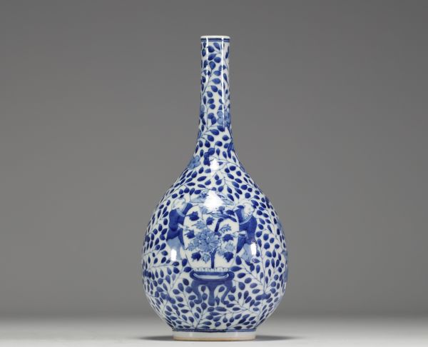 China - White-blue porcelain vase decorated with a figure holding a large covered vase, double circle mark under the piece.