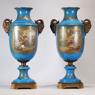 Pair of monumental Sèvres porcelain vases decorated with bronze rams' heads and painted with romantic scenes on a blue background