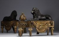 Pair of ormolu and patinated and gilt bronze andirons representing lions lying in front of a flame, 19th century.