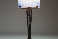 DEGUÉ - David GUERON (1892-1950) - Lampe Art Nouveau en métal forgé décor végétal et obus en verre à coloration intercalaire, signée.