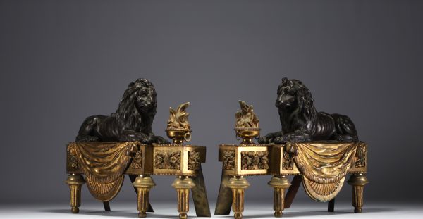 Paire de chenets en bronze patiné et doré représentant des lions couchés devant une flamme, XIXème.
