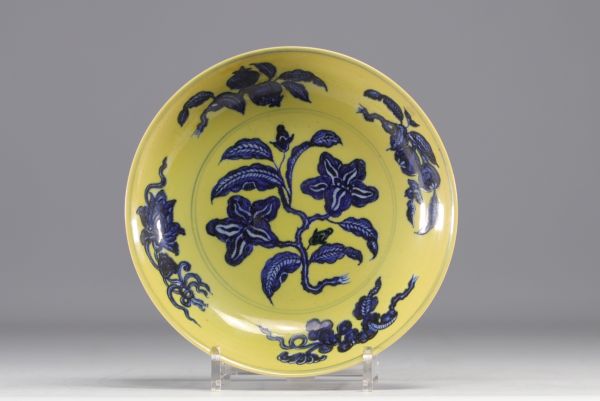 Chine - Plat en porcelaine à décor de fleurs en blanc et bleu sur fond jaune, marque en bleu.