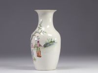 A Famille Rose porcelain vase decorated with figures and a tree on a white background