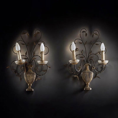 A pair of patinated metal sconces decorated with antique-style vases.