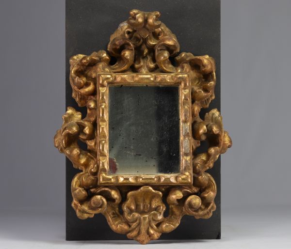 Miroir en bois sculpté doré à décor de coquille et palmettes.