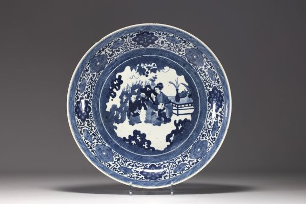 China - Large blue-white porcelain dish decorated with flowers and figures, Kangxi mark in a double circle.