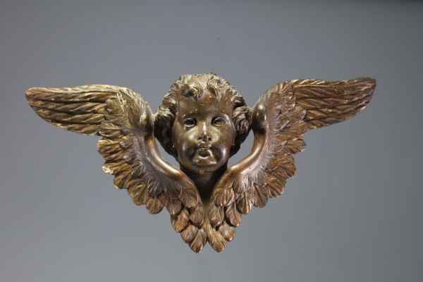 An 18th century carved wooden cherub with open wings.