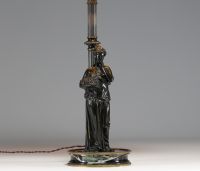 Lampe en bronze représentant une femme à l'antique adossée sur une colonne, socle en marbre noir.