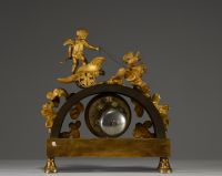 Pendule en bronze à deux patines figurant un putti dans son char tiré par deux colombes, frise à l'antique sur le socle.