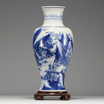 Chine - Vase en porcelaine blanc bleu à décor de paysage et personnages, socle en bois, marque au bleu sous la pièce.