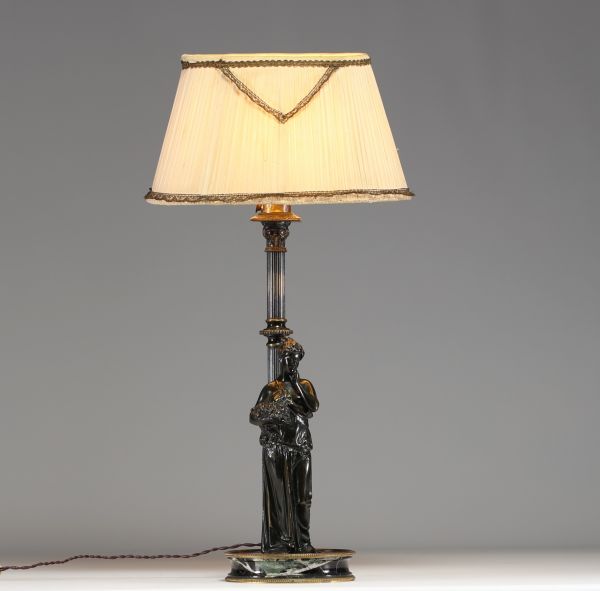 Lampe en bronze représentant une femme à l'antique adossée sur une colonne, socle en marbre noir.